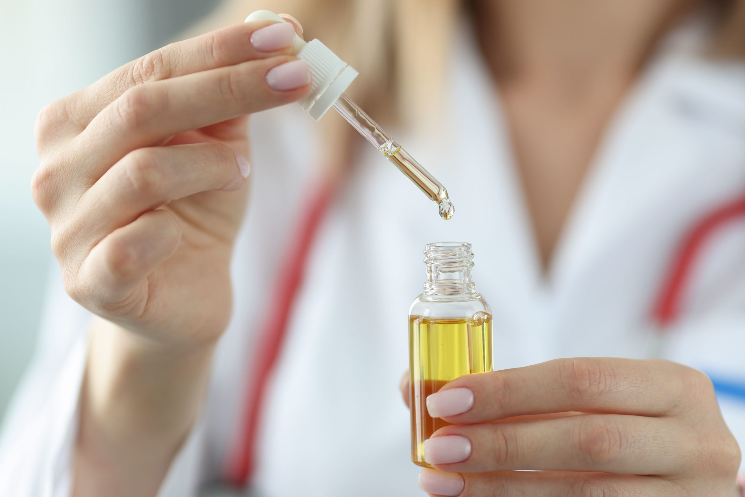doctor dripping cosmetic oil from pipette